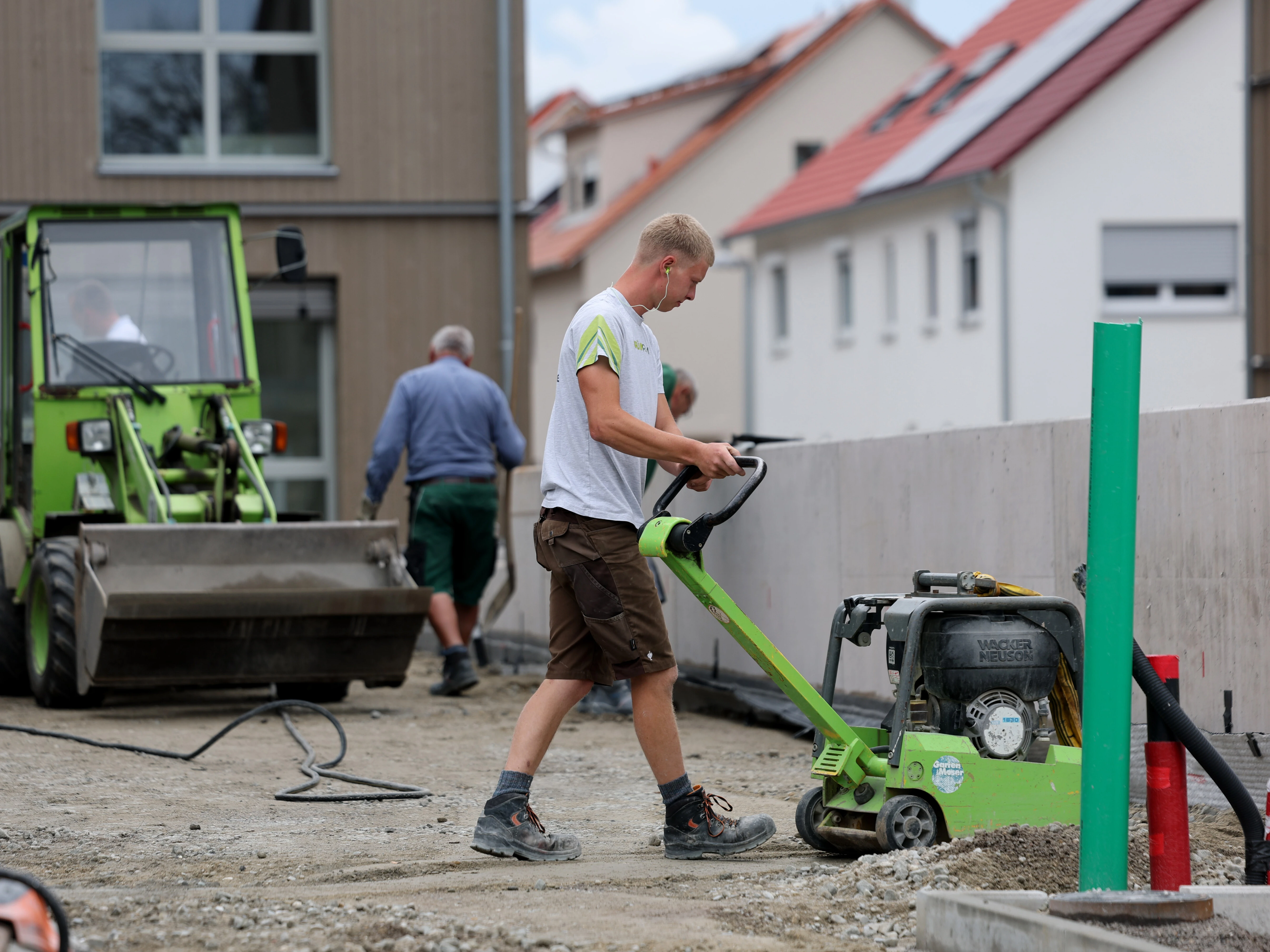 Mitarbeiter von Garten Moser positioniert einen Betonblock mit einer Hebevorrichtung vor einem Wohnhaus